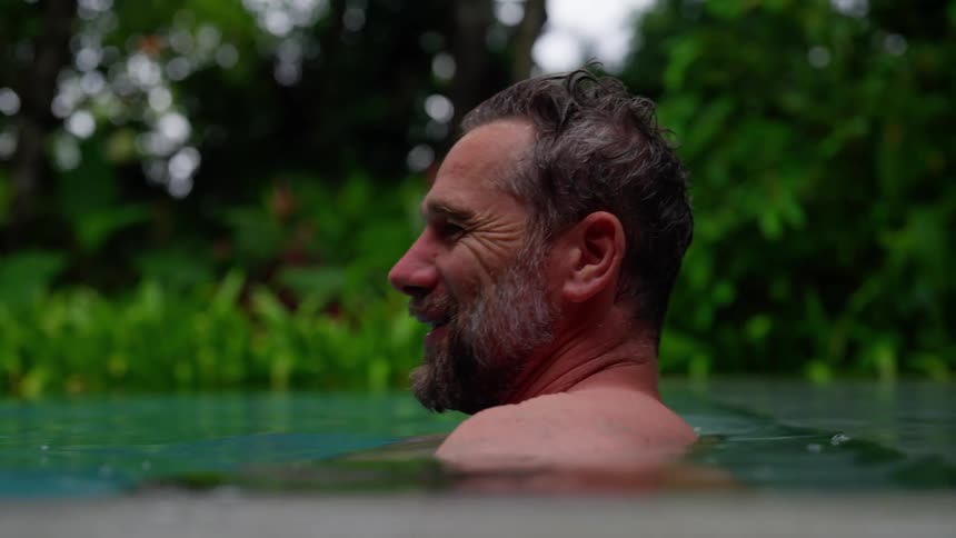 Man smiles while relaxing in a tropical pool