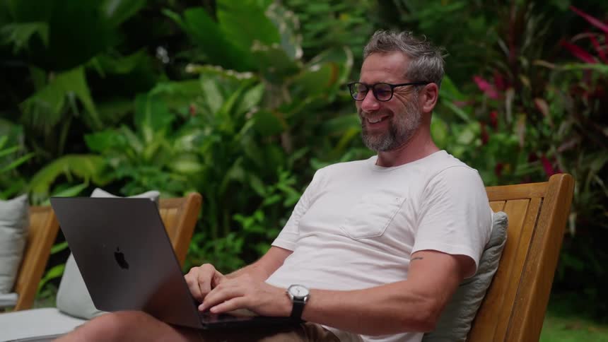 The man laughs while using his laptop