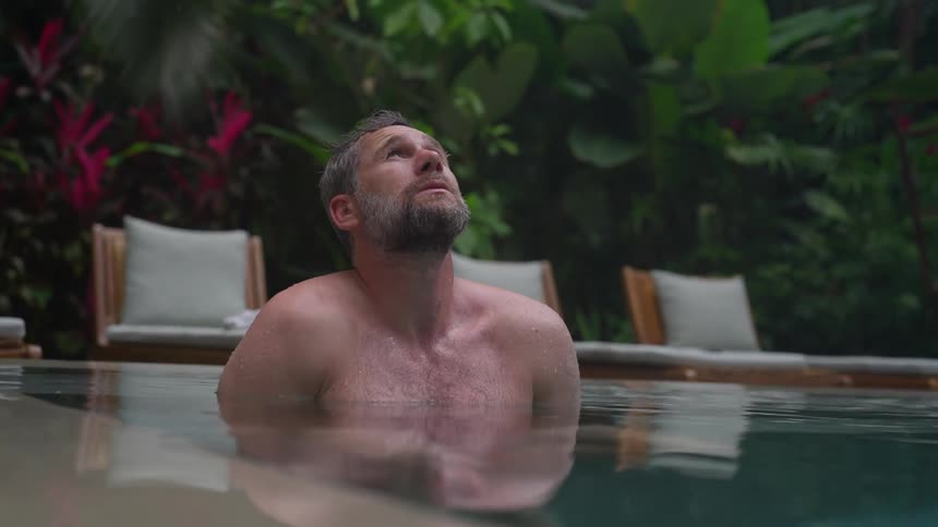 A man looks up while relaxing in a tropical swimming pool