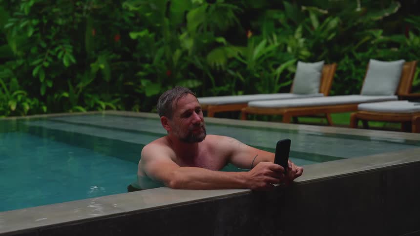 Man in the pool talking on his smartphone