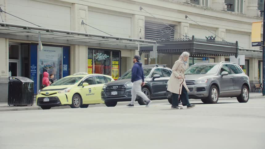 An elderly woman crosses the street