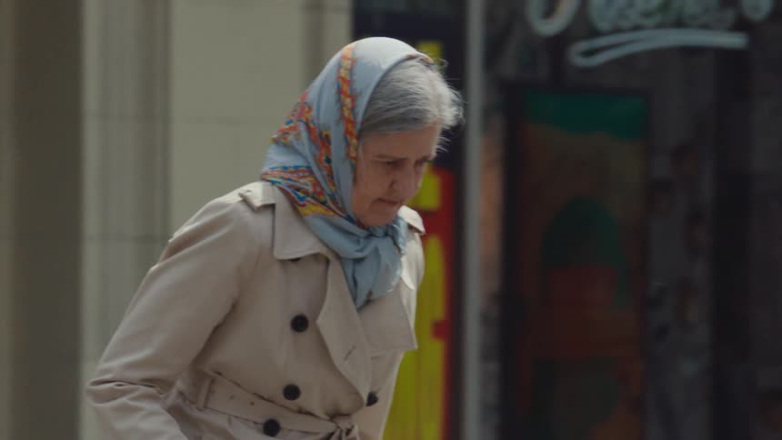 Elderly woman with a headscarf and a cane crossing the pedestrian crossing