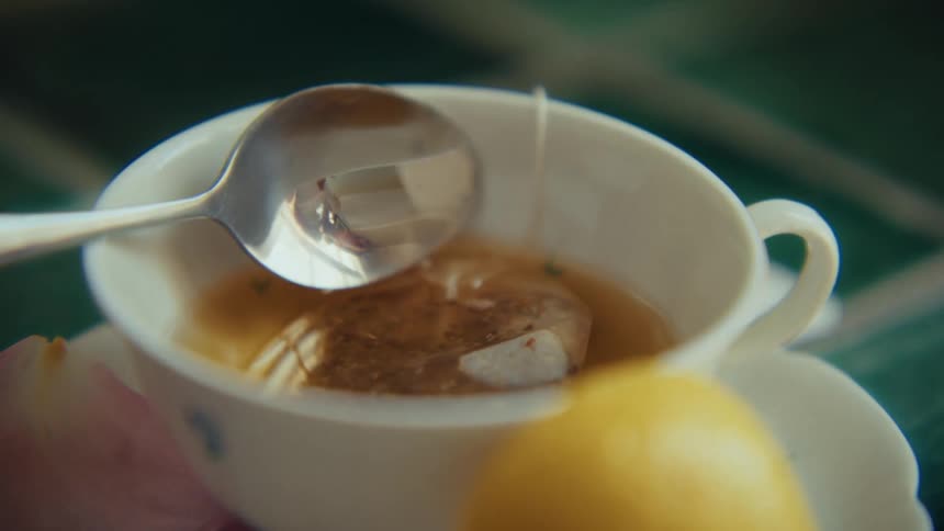 Abstract reflection of a person through a small spoon in a mug with tea