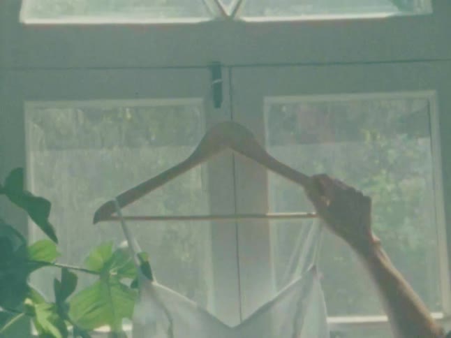 A footage of a lady hanging a cloth on the window