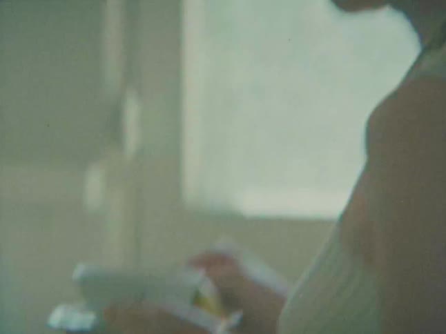 A person with a decorative necklace drinks from a cup then places it on a tiled countertop