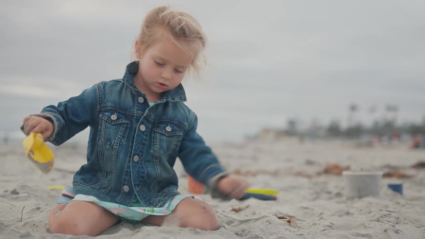 Little girl playing in the sand on the beach