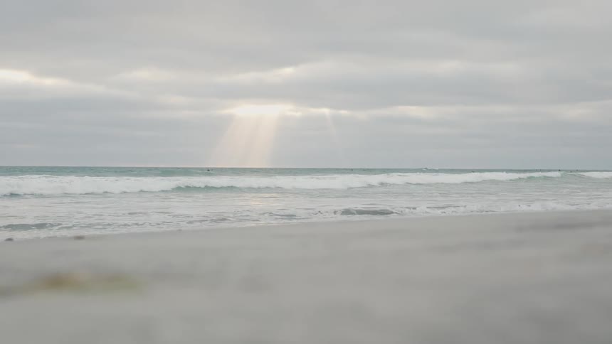 Sunbeams filtered through overcast clouds on the beach