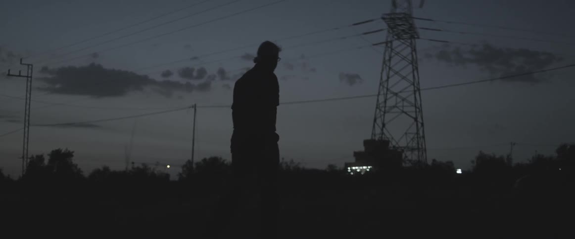 A man walks outside at dusk