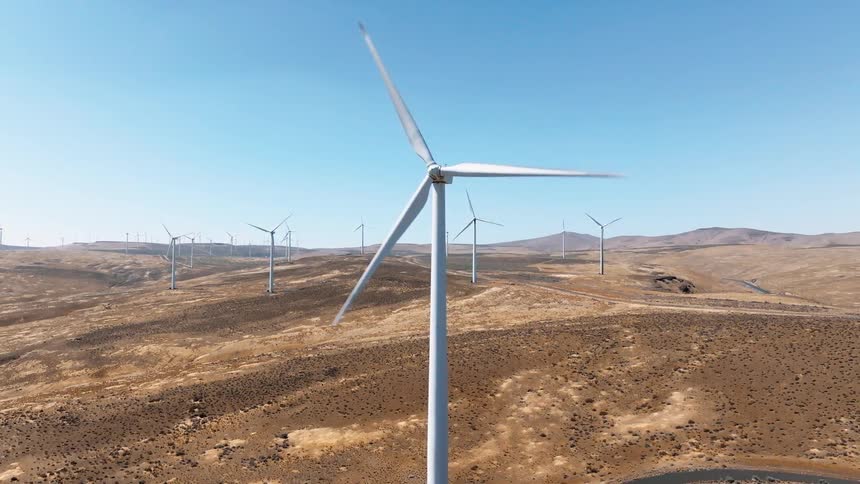 The tall windmills turn together in the wind farm