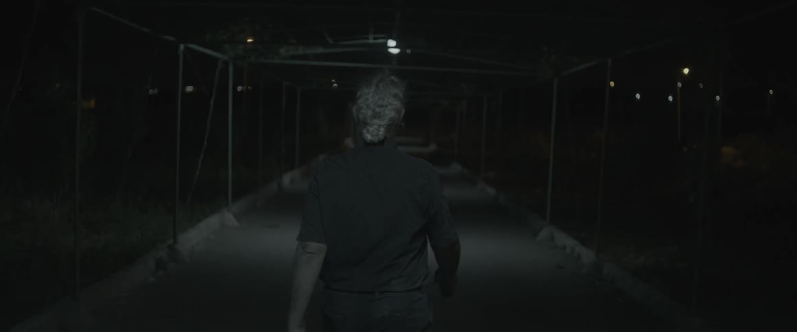 A man walks outdoors on a dark night