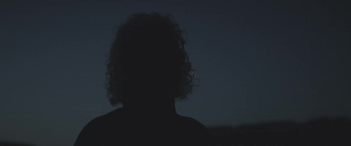 A man looks up at the dark night sky