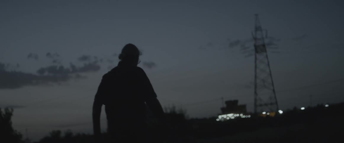 An elderly man walks outside in the evening