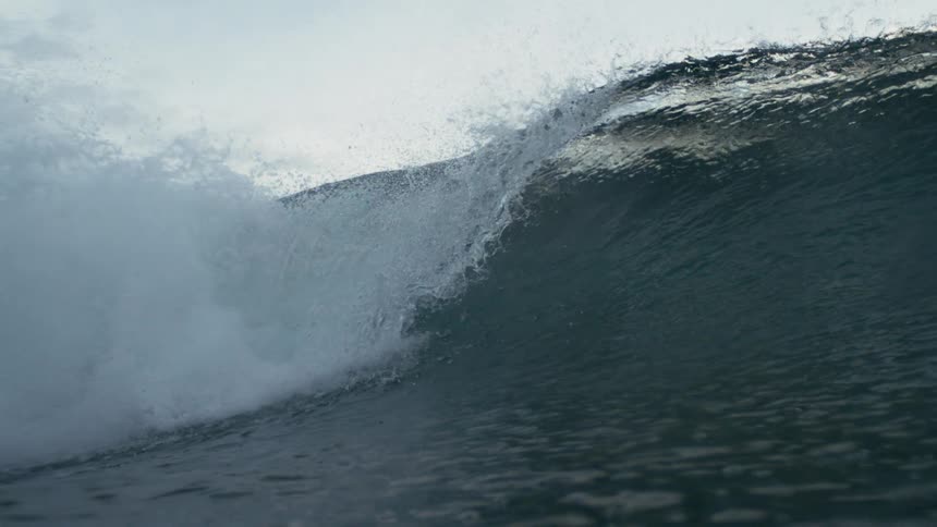 A hug waves forms and crashes across the ocean surface during daytime