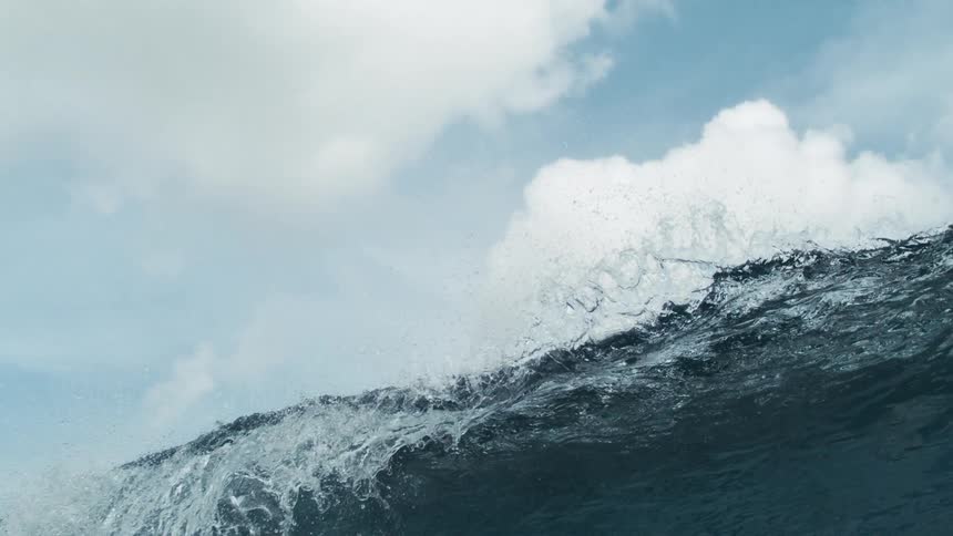 A large ocean wave curls upward under a cloudy sky