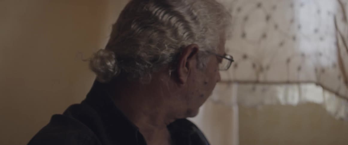 A man turns as a curtain blows