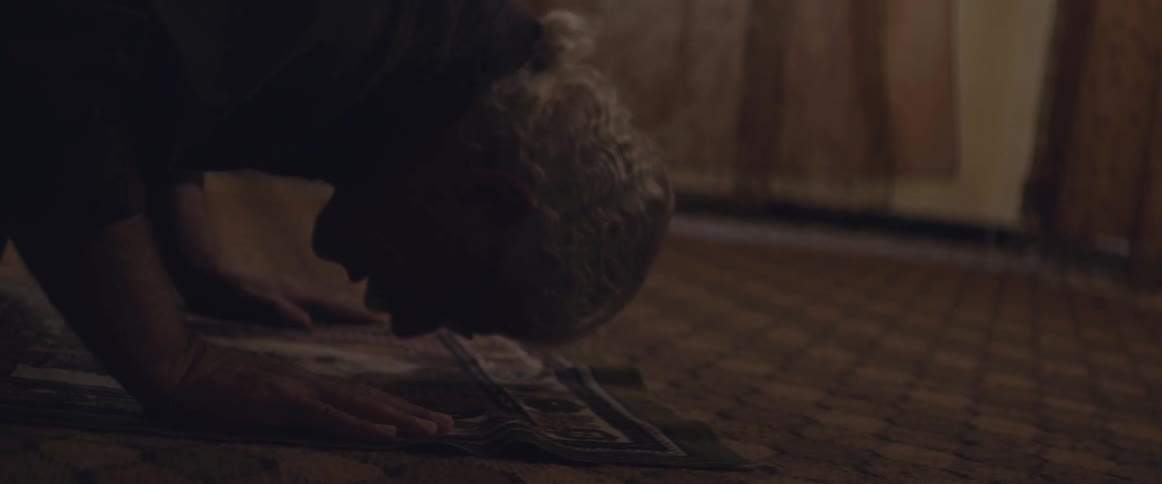 A man kneels on the floor to pray