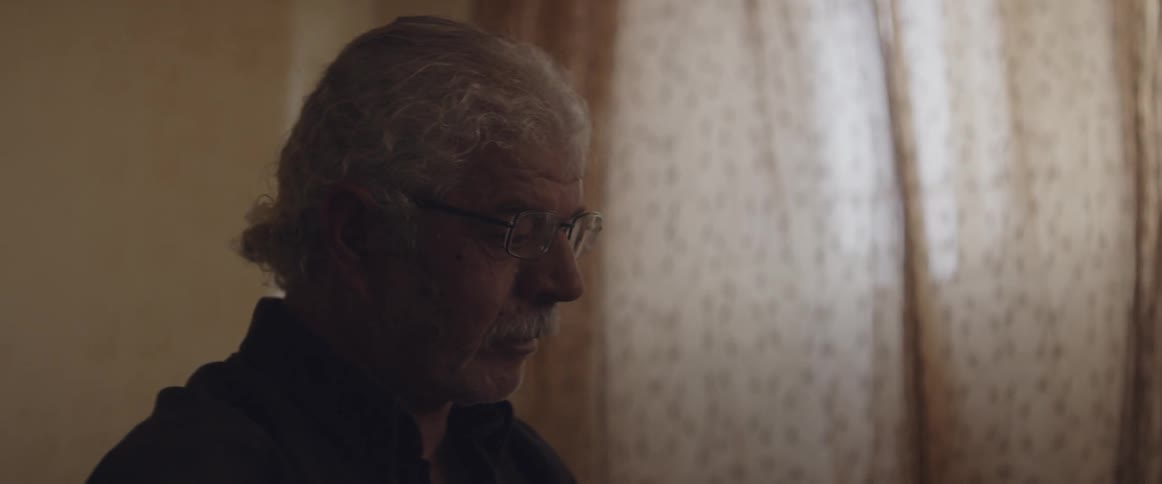 Man wearing glasses with eyes closed in a room