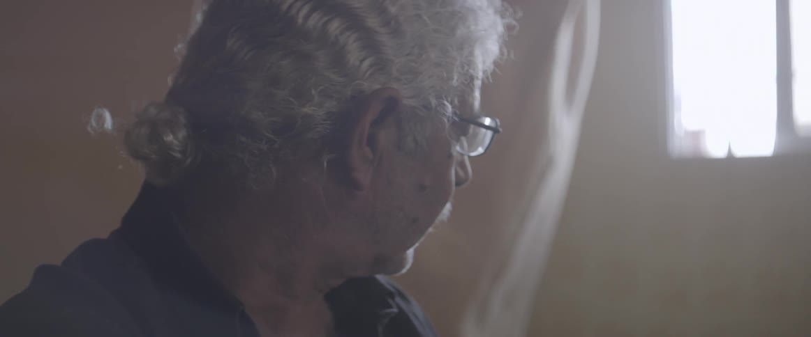 A curtain billows behind an elderly man