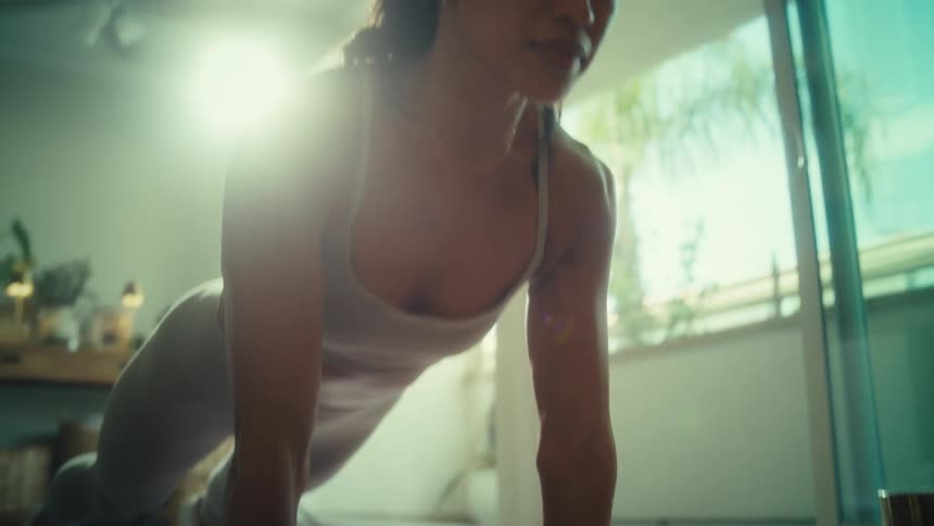 A young woman indoors exercising by doing pushups