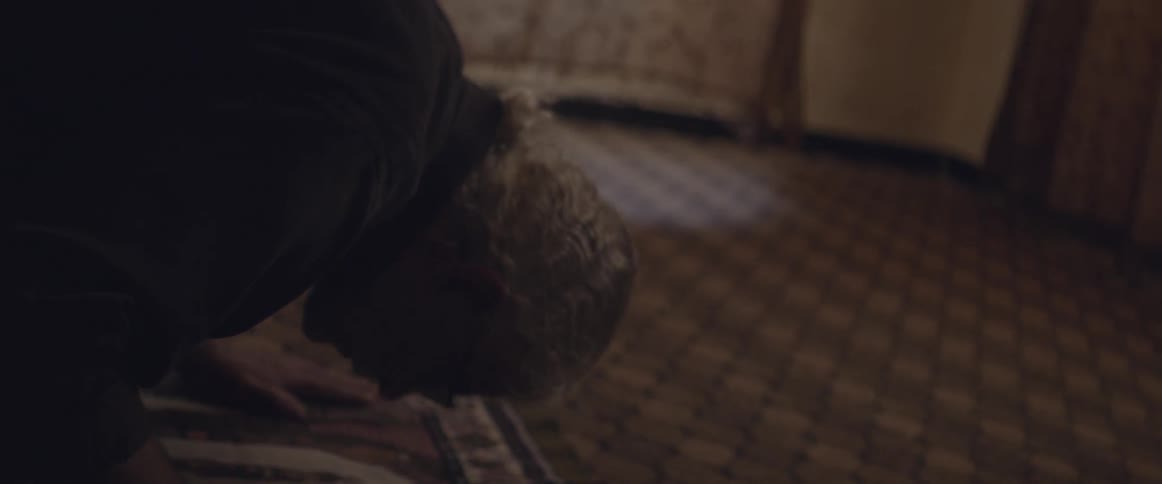 A man is praying in a dark room