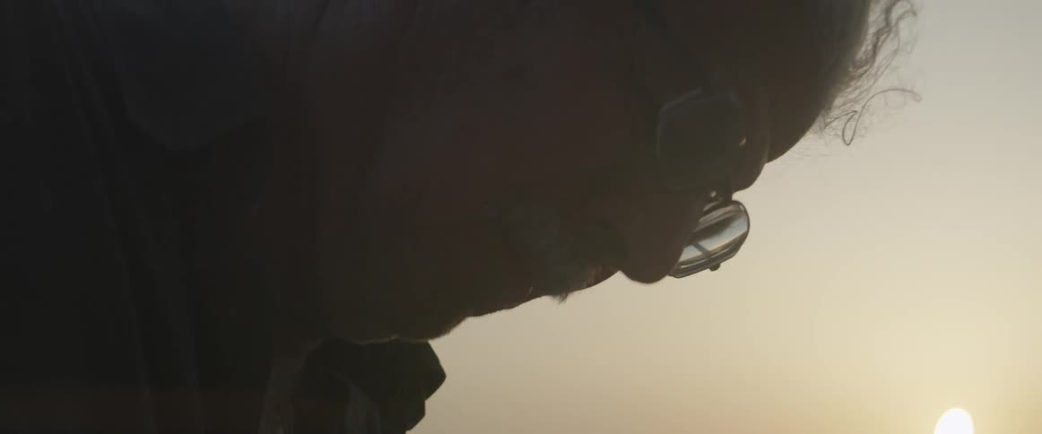 An elderly man looks down outdoors