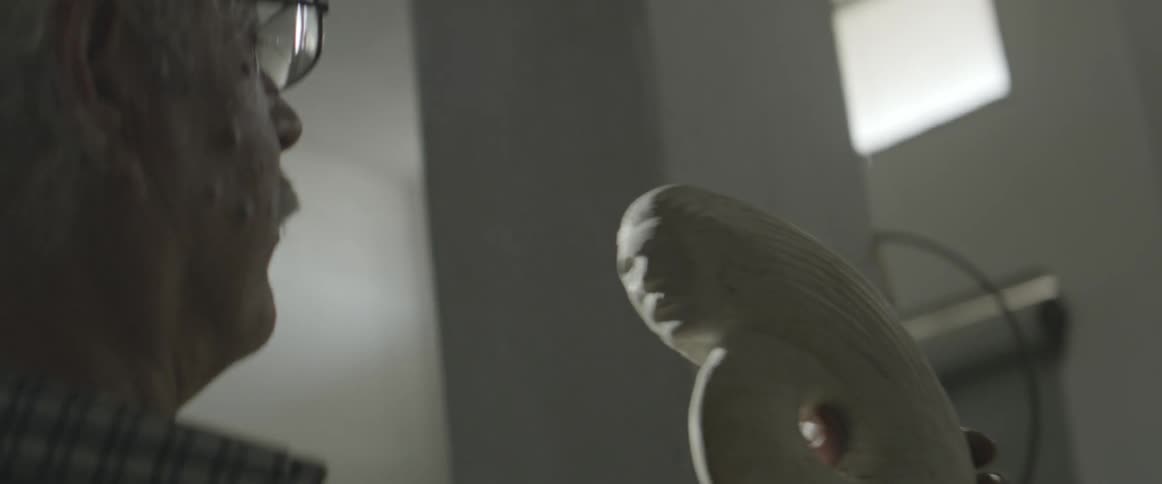 A man blows dust off a sculpture