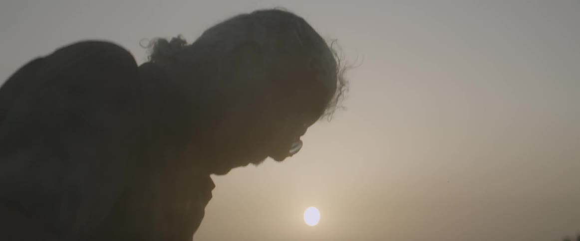 Dust swirls around a man as the sun shines overhead