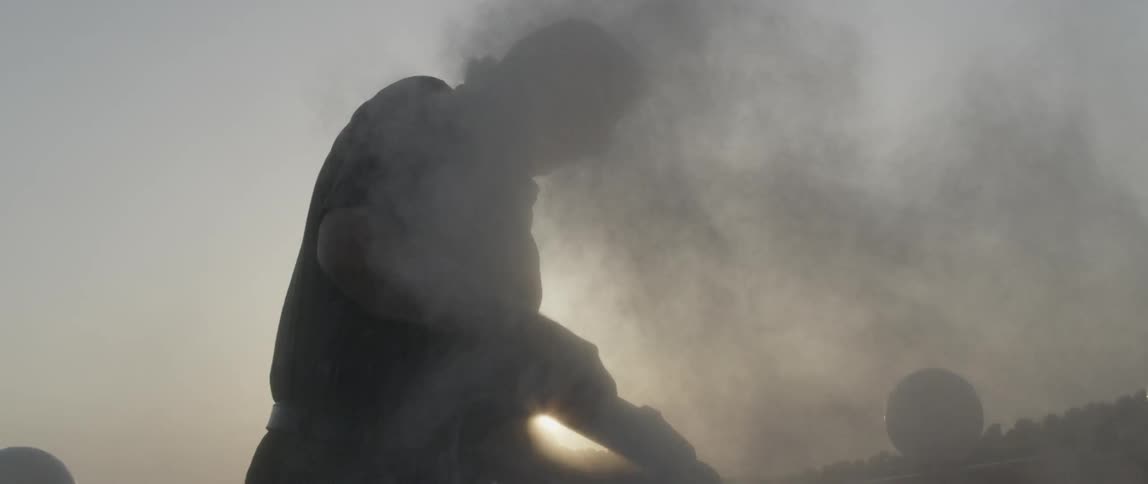 A man works with a grinder outside