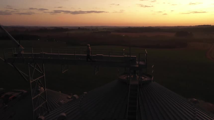 Grain silos stand tall in a rural landscape at sunset