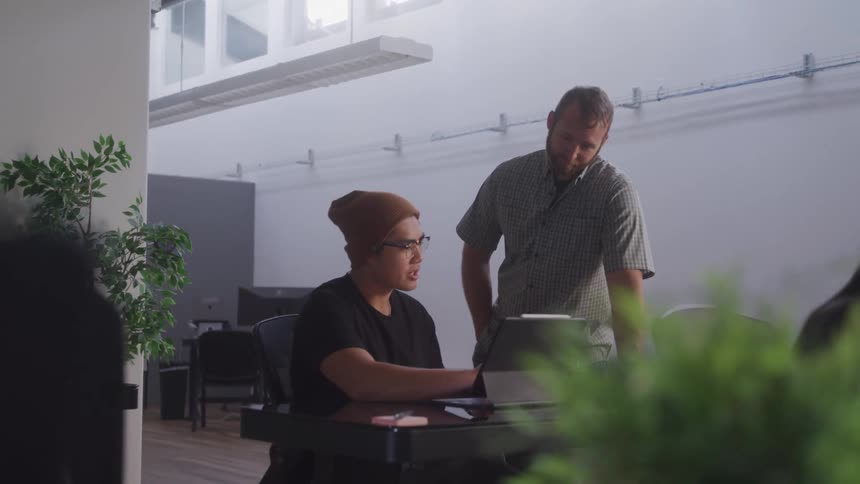 Two men engaged in a focused discussion at a desk within a modern office setting