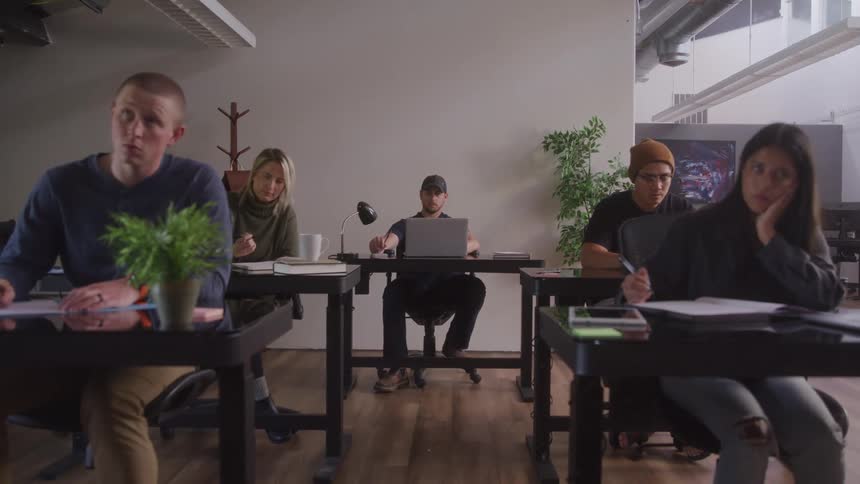 Students taking notes at individual tables in a small open classroom