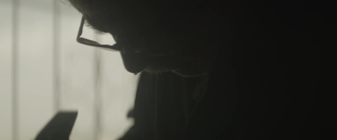 A man works in a dim room near a window