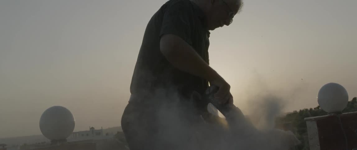 A man uses a power tool to grind a rock
