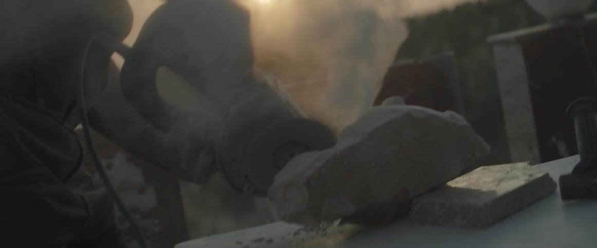 A man works with a grinder on a sculpture