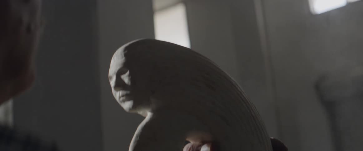 A man blows dust from his rock sculpture