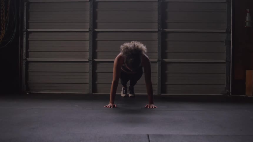 Fit female doing pushups indoors on concrete floor