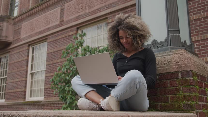 A student uses her laptop outside the school