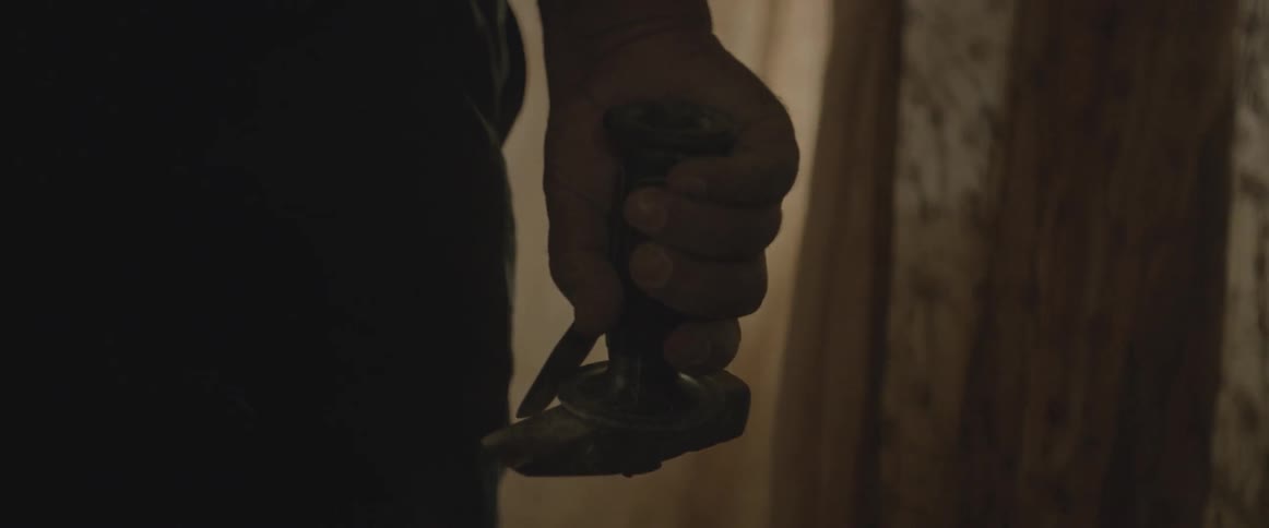 A man walks towards a window with a hammer and chisel