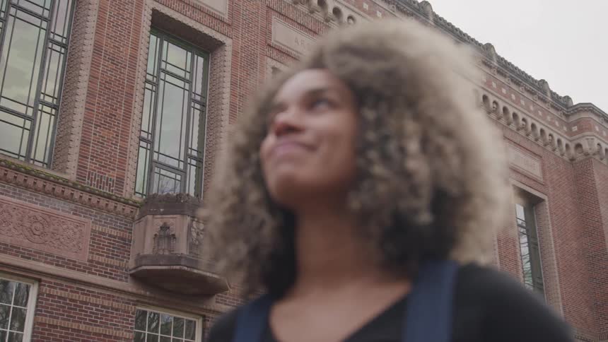 Smiling woman out of focus in front of a historic brick building