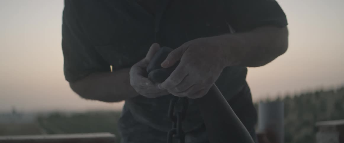 Man sculpting clay outdoor at sunset
