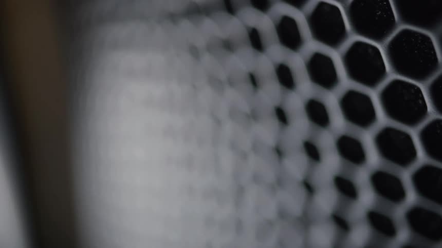 The video displays a closeup of a perforated metal surface with a hexagonal pattern the focus shifts across the grid highlighting the depth and texture of the material likely a speaker grille or similar mesh