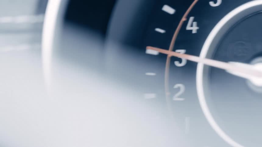 The camera shakes as it captures a close view of a cars tachometer with an orange needle bouncing between the numbers