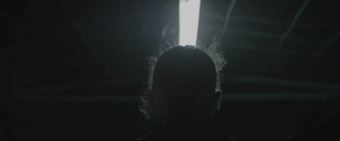 A man walks beneath an overhead fluorescent light at night