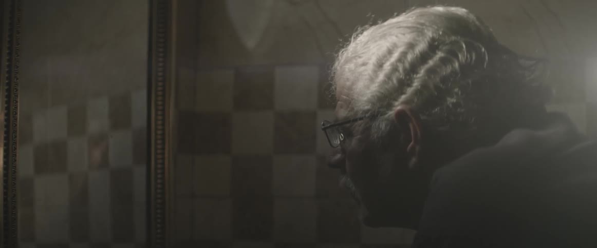 An elderly man looks into a mirror at his reflection