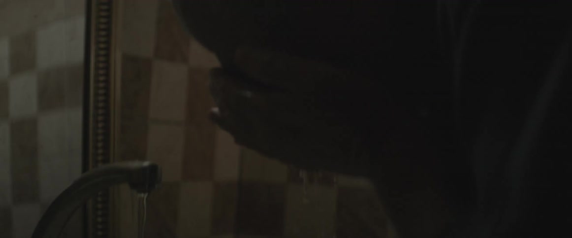 A man washes his face at a bathroom sink