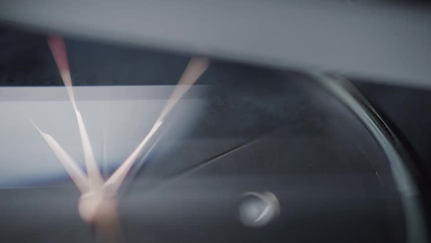 The video provides a closeup abstract view of a clock face likely a wristwatch with its hands in motion the lighting shifts causing the clock face to alternate between dark and light creating reflections and glints off the surface