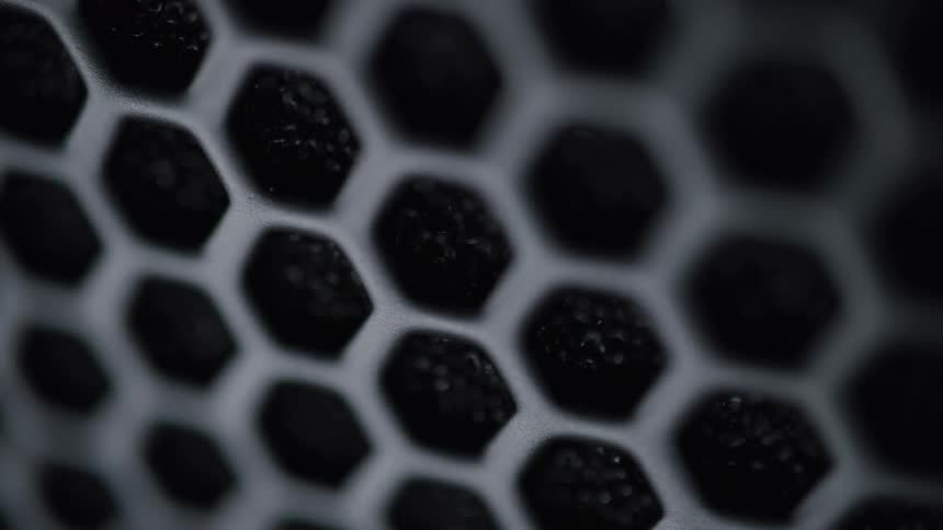 The video features a closeup of a honeycombpatterned surface possibly a filter or grille with visible texture within each hexagonal cell the lighting changes making the pattern appear darker at times before becoming more defined and lighter again