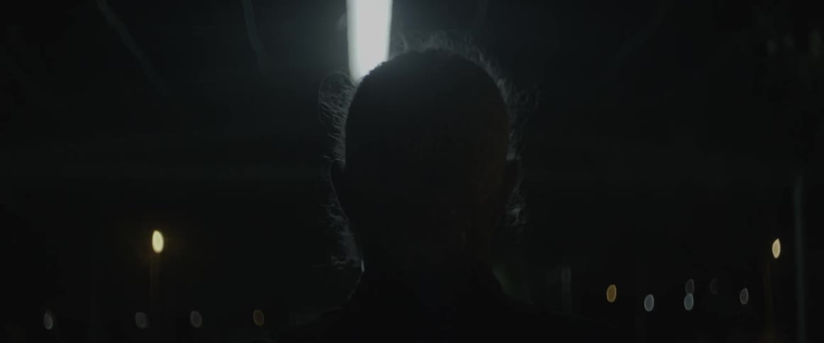 A man walks beneath an overhead fluorescent light