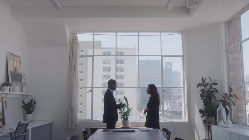 A man and woman talk in the office conference room