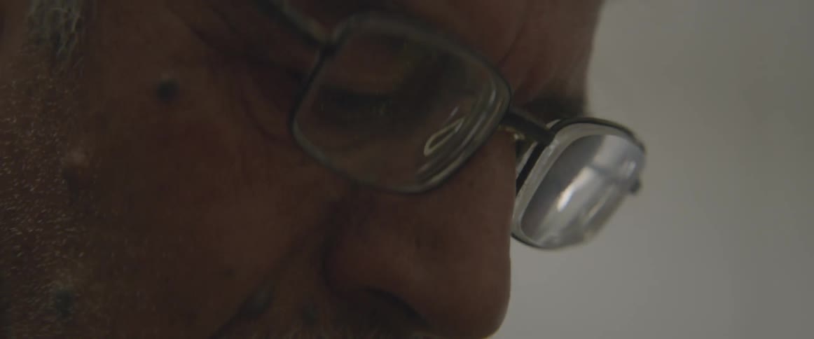A man with a mustache looks down